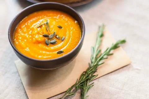 Pumpkin soup decorated on a table with a sprig of rosemary Foto stock