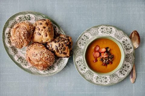 Pumpkin soup with fresh corn bread porcelain plates green background copy space Stock Photos