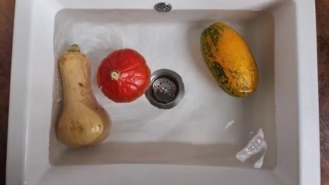 Pumpkin spinning in water in kitchen sink close up Video stock 330898726