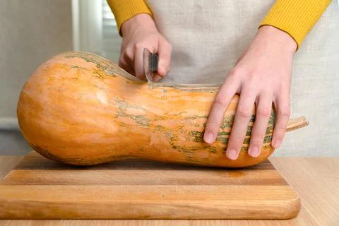 Pumpkin on the table, hands with a knife cut a vegetable. Stock Photos