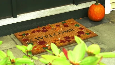 Pumpkin welcome mat under front door with leaves Stock Footage 140930491