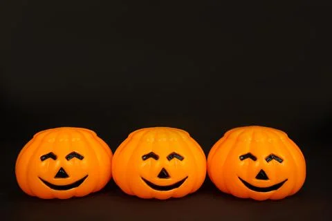 Pumpkins are orange, plastic with smiling faces on a black background Stock Photos