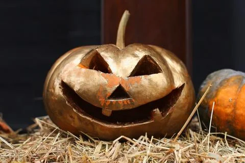 Pumpkins with a carved face lie in the hay. Halloween preparation, rustic sty Foto stock