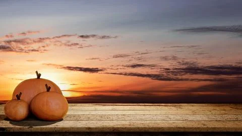 Pumpkins on rustic wooden table with sunset scene background. Concept of Th.. Stock Photos