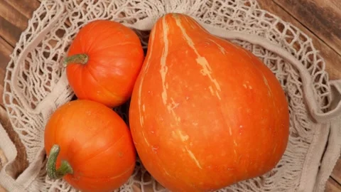 Pumpkins in string bag rotate on wooden background. concept of eco products. Stock Footage 242174573