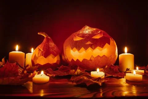 Pumpkins with terrifying carved faces on red background lit by candles Stock Photos