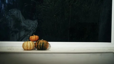 Pumpkins in window with ghost in the background Stock Footage 323123425