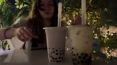 Punch a bubble tea with a straw evening cafe young european girl drinks cold Stock Footage 286126334