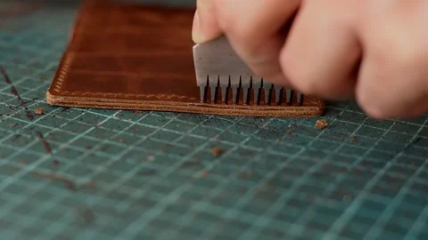Punching holes in the leather work piece with a metal puncher. Stock Footage 150480086
