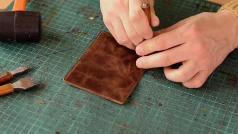 Punching holes in the leather work piece with a metal puncher. Stock Footage 150480248