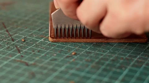 Punching holes in the leather work piece with a metal puncher Stock Footage 150480260