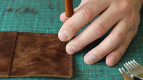 Punching holes in the leather work piece with a metal puncher. Stock Footage 150480336