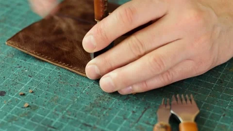Punching holes in the leather work piece with a metal puncher. Stock Footage 150480451