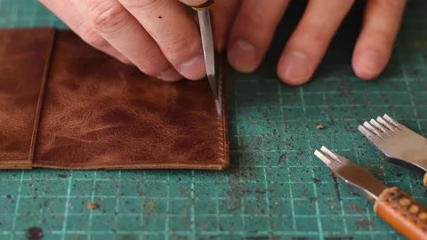 Punching holes in the leather work piece with a metal puncher. Stock Footage 150480495
