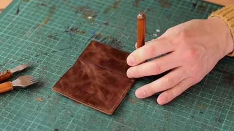 Punching holes in the leather work piece with a metal puncher. Stock Footage 150480512