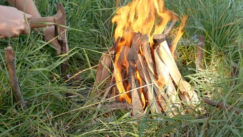 Punching a peg into the ground near the fire. Stock Footage 119369900