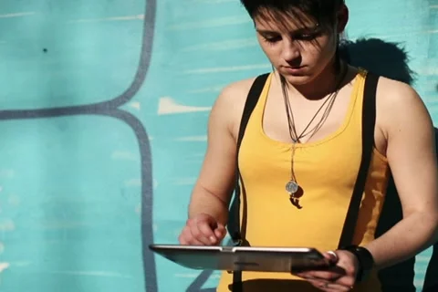 Punk girl with tablet computer standing by the wall, steadicam shot NTSC Stock Footage