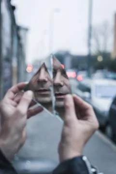 Punk guy looking at himself in a shattered mirror Stock Photos