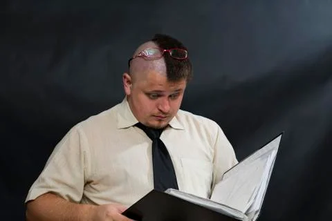 Punk is reading a work log. Glasses shifted on the forehead. White shirt, dark Stock-Fotos