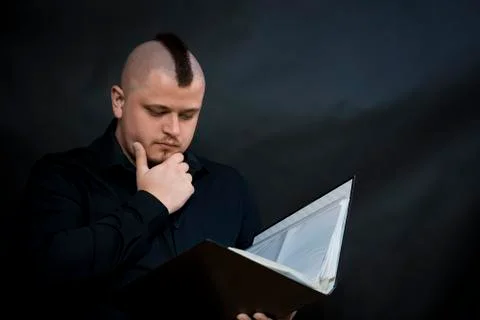 Punk reading a working folder. Black shirt. Iroquois. Sight attentive and Stock Photos