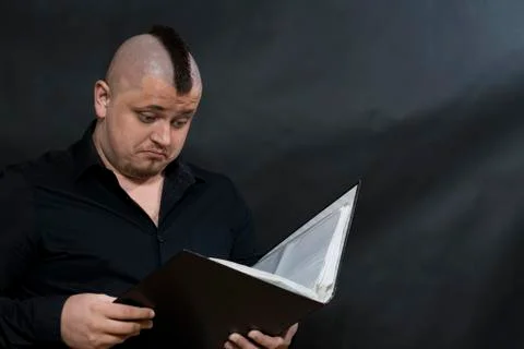 Punk reading a working folder. Black shirt. Iroquois. Sight attentive and Foto stock