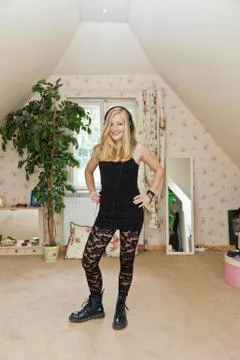 A punk teengirl standing in a conservatively decorated bedroom Stock Photos