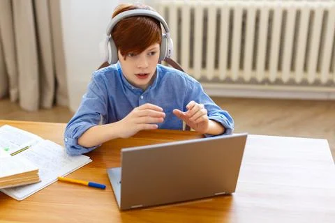 A pupil during in front of laptop talks to the teacher or peers and makes act Stock Photos