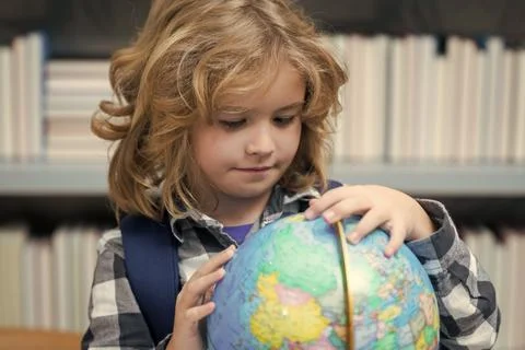 Pupil looking at globe in library at the elementary school. Nerd school kid Stock Photos