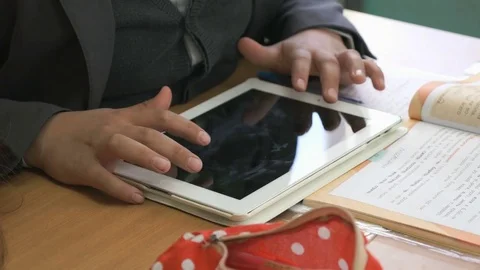 Pupil plays in games using white computer tablet Stock Footage