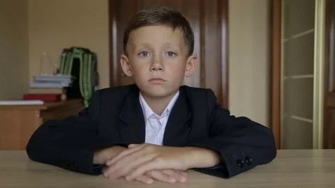A pupil in school uniform sits at a desk Stock Footage
