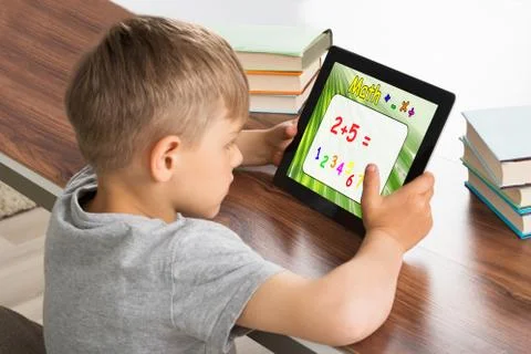 Pupil Solving Math Problem On Digital Tablet With Stack Of Books On Desk Stock Photos