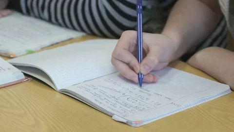 Pupil writes text in a exercise book using a pen Stockbeeldmateriaal 69232912