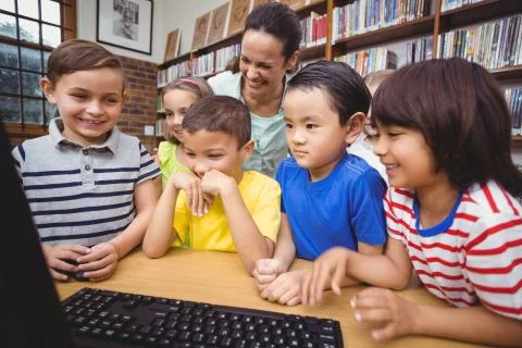 Pupils and teacher in the library using computer 스톡 사진