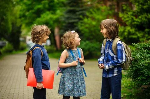 Pupils of elementary school about something cheerfully talk on the schoolyard Stock Photos