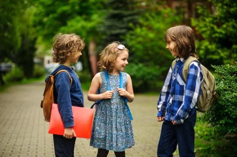 Pupils of elementary school about something cheerfully talk on the schoolyard Stock Photos