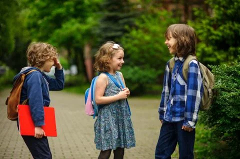 Pupils of elementary school about something cheerfully talk on the schoolyard Stock Photos