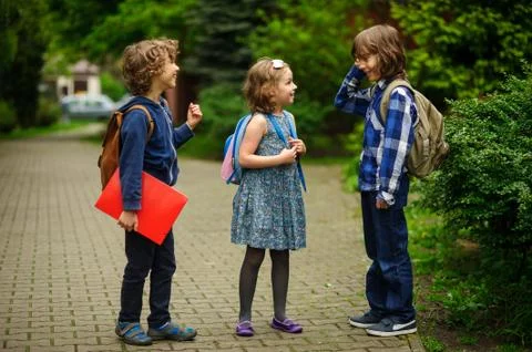 Pupils of elementary school about something cheerfully talk on the schoolyard Stock Photos