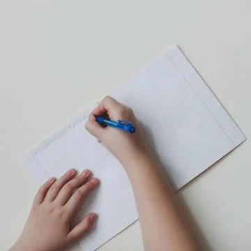 Pupil's hands writing in open notebook, top view, copy space Stock Photos
