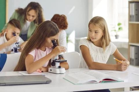 Pupils-partners for practical work look into microscope during biology lesson in Foto stock