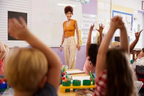 Pupils Raising Hands To Answer Question In Elementary School Maths Lesson Stock Photos