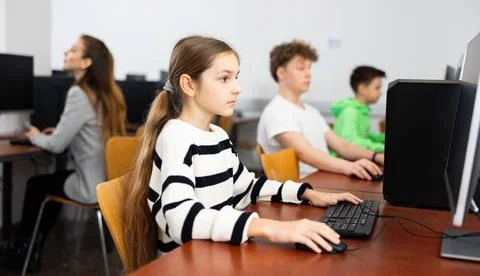 Pupils using computers at lesson, teacher teaching them in class room Foto stock