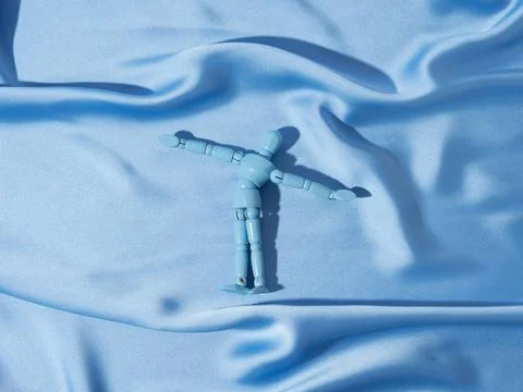 Puppet on blue satin texture background as man swimming in ocean sea concept Stock Photos