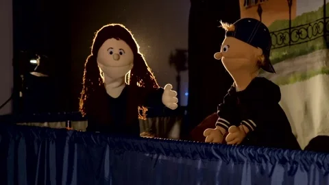 Puppet dolls gesturing behind table during indoor theater performance Stock Footage 340887243