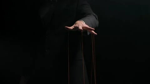 Puppet Master controls and manipulates the puppets with strings attached to his Stock Footage 146638147