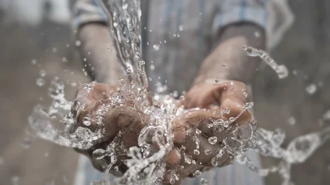 Pure and freshwater water falling on poor man's hands against dry farmland Stock Footage
