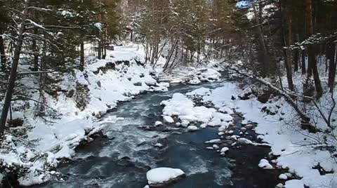 Pure blue mountain river flowing among the snow-covered shores Stock Footage 20588804