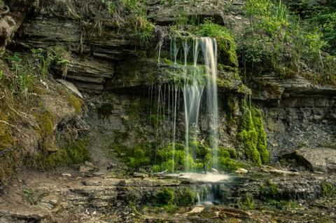 Pure cold water flows through rock covered with moss Foto stock