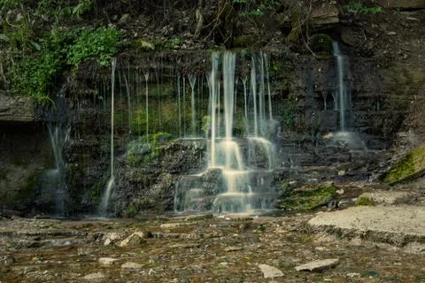 Pure cold water flows through rock covered with moss Stock Photos