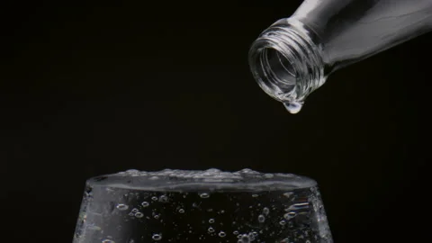 Pure drops falling glass full of mineral water close up. Wineglass filled drink. Vidéo 212389915