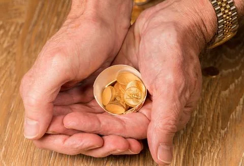 Pure gold coins in egg shell illustrating nest egg Senior man s hand holdi... Stock Photos